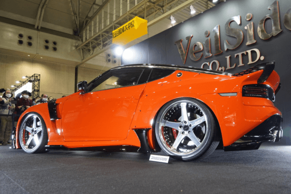 Rear-side view of VEILSIDE FFZ400 RZ34 at auto show, highlighting the full aero kit and deep-dish wheels.