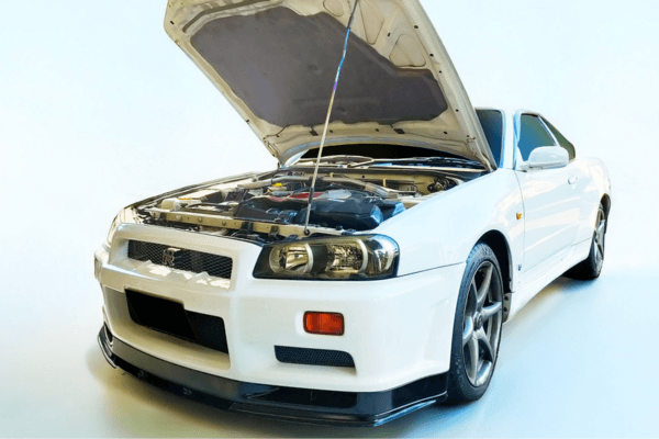 Installed FUJITSUBO EXH+ Hood Support holding open the hood of a Nissan Skyline GT-R BNR34, showcasing fitment and design.