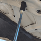 Close-up of FUJITSUBO EXH+ Hood Support attachment to hood of Skyline BNR34, showing resin holder and titanium rod detail.