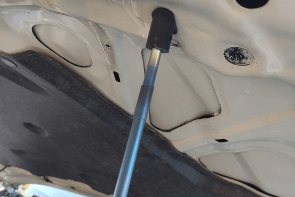 Close-up of FUJITSUBO EXH+ Hood Support attachment to hood of Skyline BNR34, showing resin holder and titanium rod detail.