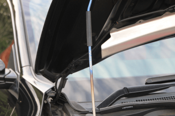 Detailed view of FUJITSUBO EXH+ Hood Support rod with protective sticker and burnt titanium finish on Civic Type R FK8.
